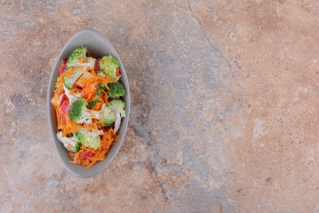 Bowl of salad is sitting on the granite counter