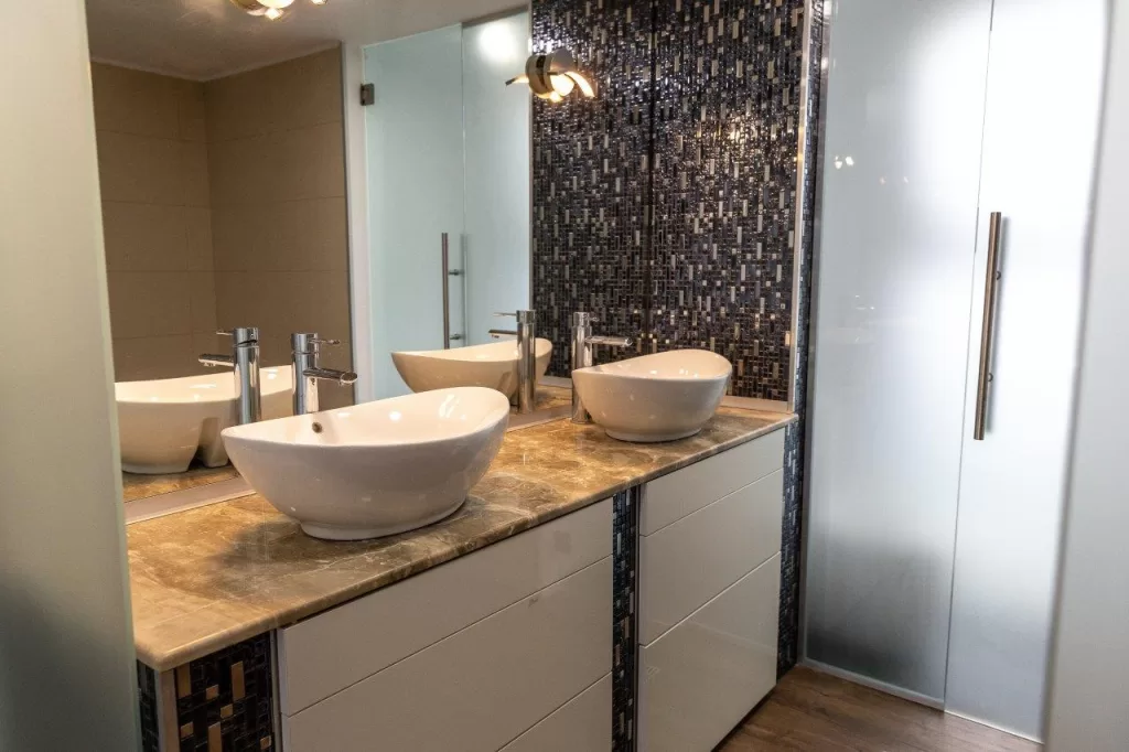 Interior of a bathroom with two sinks, a big mirror and a patterned wall
